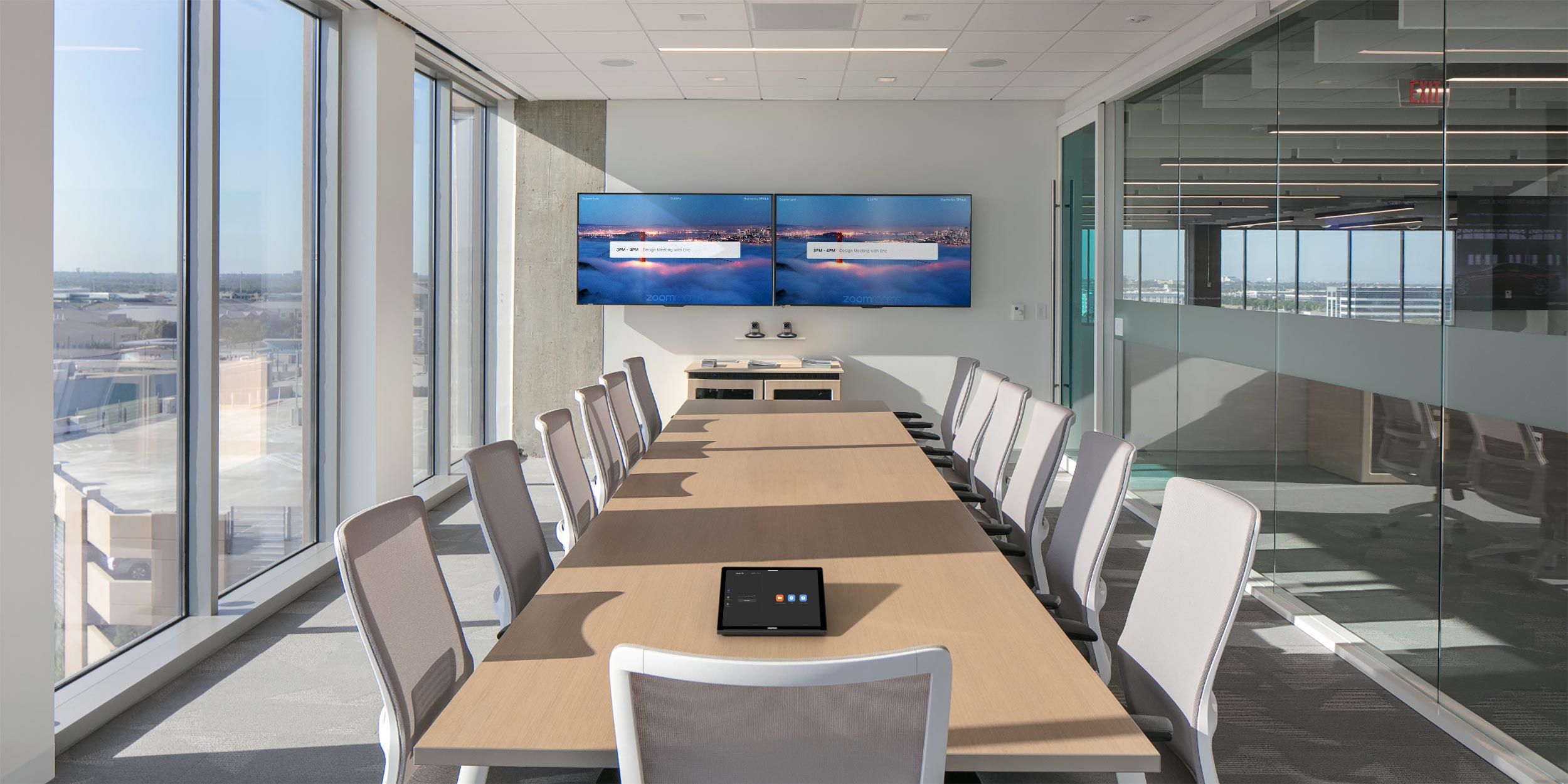 A modern conference room with a long table, dual screens on the wall, and glass walls providing a panoramic view.