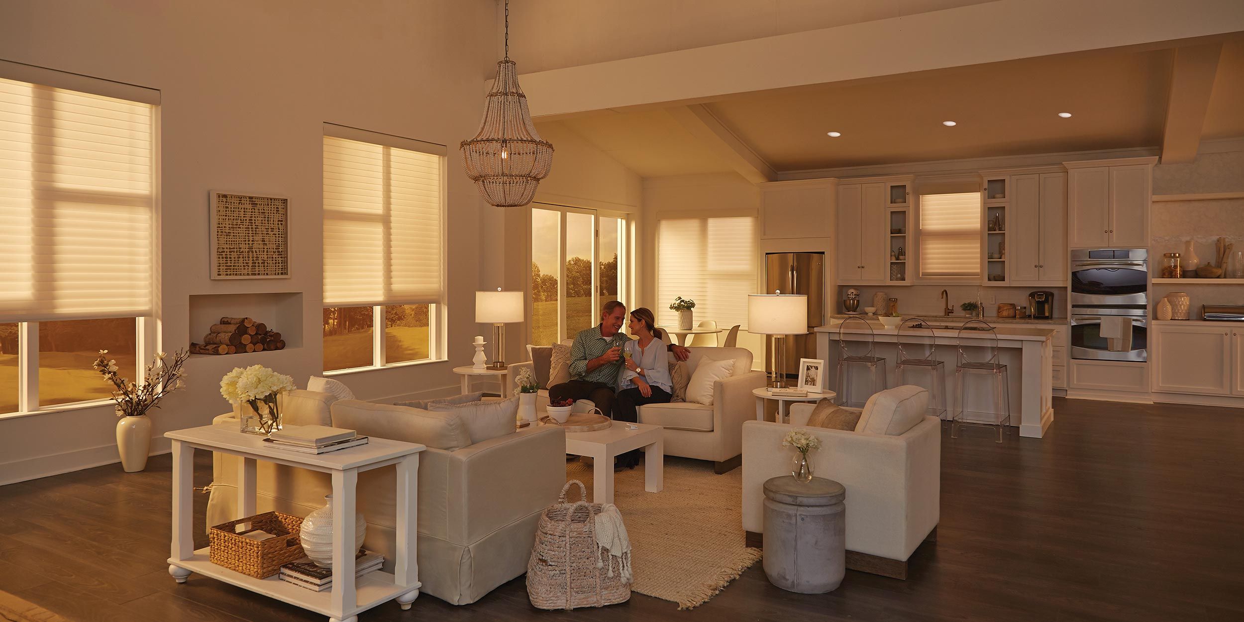 A cozy living room bathed in warm natural light, with a couple sitting on a sofa enjoying a relaxed moment.